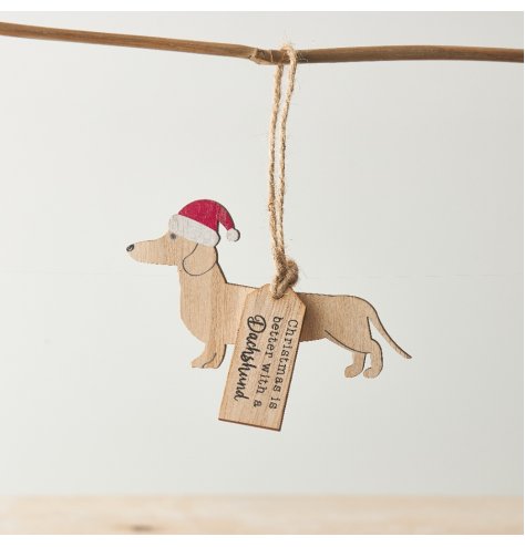 A wooden decoration with dachshund silhouette, red Santa hat and "Christmas is better with a dachshund" tag. 