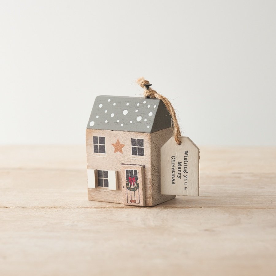 A charming wooden Christmas house with a printed slogan gift tag. 