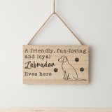 A hanging wooden sign with "a friendly, fun-loving & loyal Labrador lives here" text & illustration with paw prints.