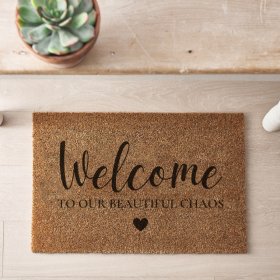 A stylish coir doormat with "Welcome to our beautiful chaos" message and heart detail. 