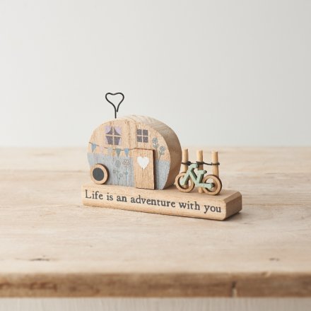 A decoration made from wood with a hippie caravan parked next to a bike, and black wording along the bottom.