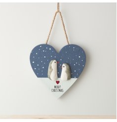 a heart shape Christmas decoration, displaying a pair of penguins standing in the snow
