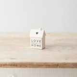 A sweet porcelain house decoration with heart motif, monochrome colour scheme and "love begins at home" message. 