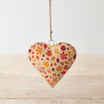 A colourful metal heart decoration with ochre, orange and brown autumnal leaves. 