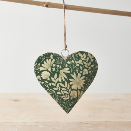 A metal heart shaped hanging decoration with a green and white floral decal. 