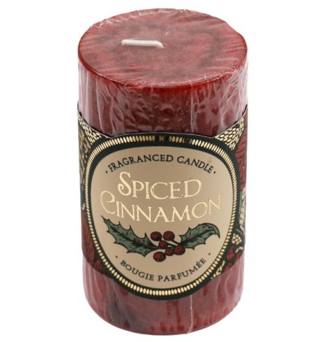 A red pillar candle in a mottled design, giving off a spiced cinnamon fragrance.