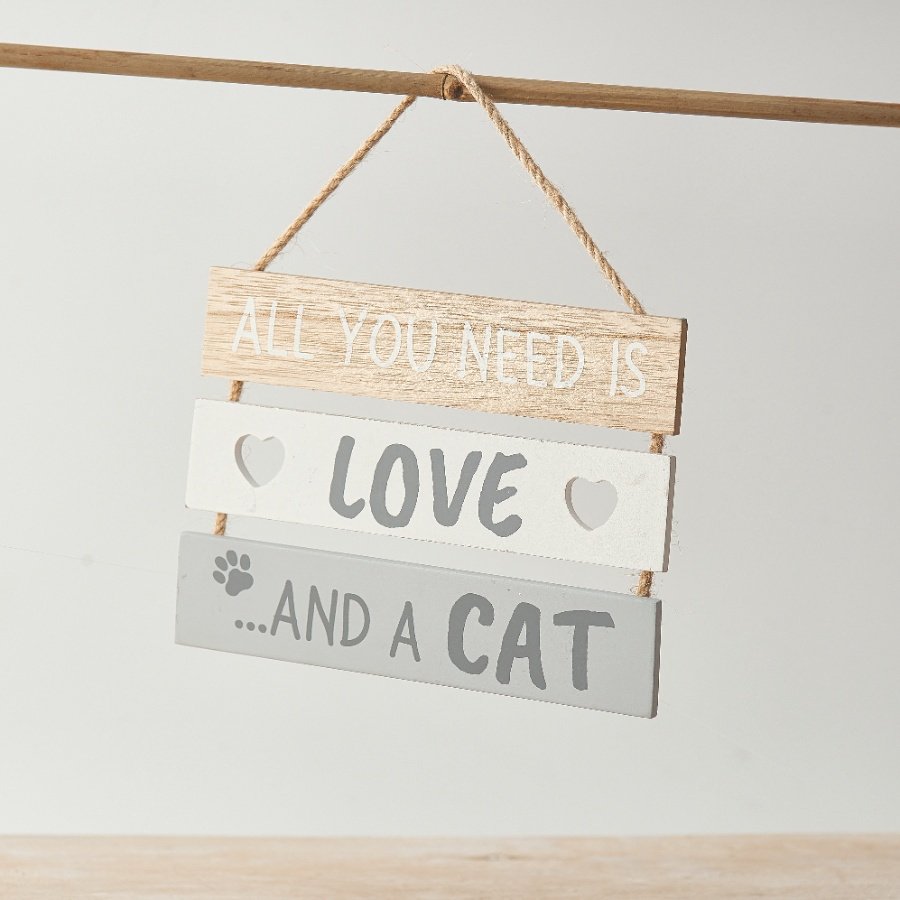 A slatted wooden sign with "all you need is love and a cat" text, heart cut motifs and a paw print detail.