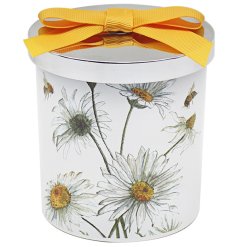 A daisy inspired candle from the Bee - tanicals range. The candle is topped with a chrome lid and a yellow bow.