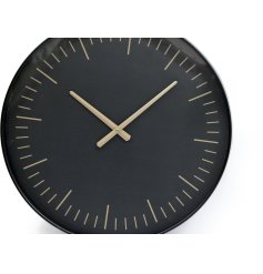 A modern wall clock in black with gold graduations and hands.