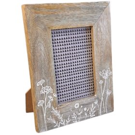A natural wood photo frame adorned with meadow flower etched detailing along the bottom. 