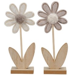 A charming flower decoration on a wooden stand with pom pom detail.