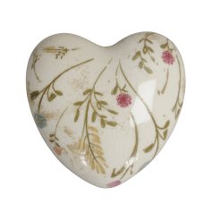 A glazed heart ornament with intricate flowers in different subtle colours.