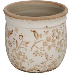 This planter with a floral design is sure to add charm to the home with its distressed look. 