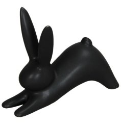 A simple black ornament in the shape of a rabbit in a downward position. 