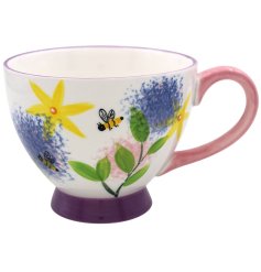 A bright and colourful footed mug covered in illustrations of alliums, bees and other flowers.
