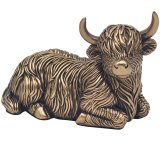 A bronze lying highland cow ornament. It features chunky horns and rugged fur detail. 