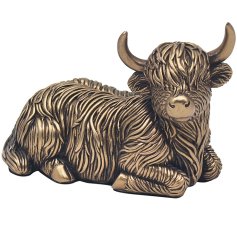 A bronze lying highland cow ornament. It features chunky horns and rugged fur detail. 