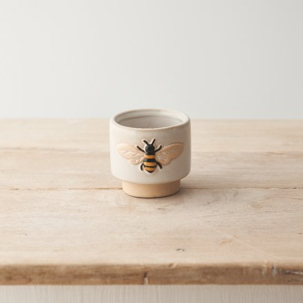 A small stoneware planter featuring a decorative bee design. 