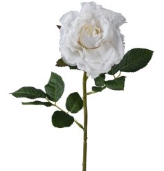 A white artificial rose with intricate petals and dark green leaves.