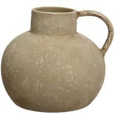 A beautifully textured vase in a natural stone hue. With a classic sculptural shape and curved handle. 