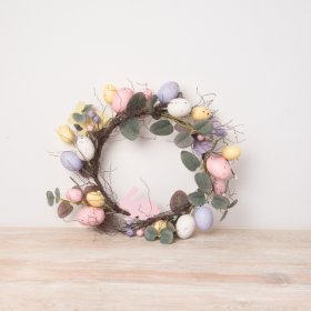 A colourful Easter wreath with whimsical branches, speckled eggs and wooden bunnies. 