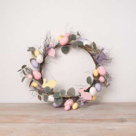A large artificial twig wreath with an abundance of pastel coloured speckled eggs and wooden rabbits.