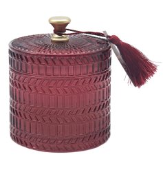 A luxury candle from the Desire range detail a patterned ruby coloured pot and a matching tassel detail.