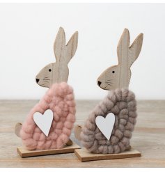 An assortment of 2 wooden rabbit ornaments in pink and grey with a sweet heart decal and woolen body.