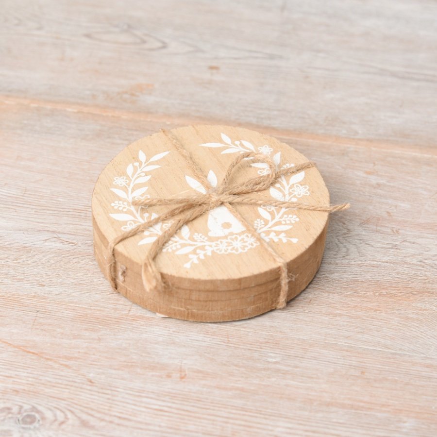 A set of 4 round wooden coasters with a printed bunny and floral wreath design. 