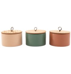 A fragranced candle encased in a ribbed candle pot with a natural wood lid, in 3 assorted designs. 