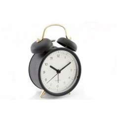 A simple yet stylish black an white bedside alarm clock with a golden handle and feet.