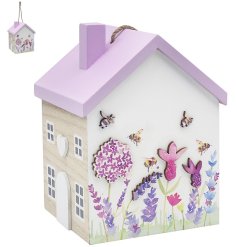 A wooden doorstop in the shape of a house with beautiful illustrations of flowers and bees. 