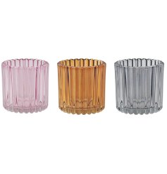 An assortment of three candle holders in shades of pink, orange, and grey.