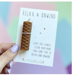 A relax and unwind candle in brown backed onto a gift card with scripted text.