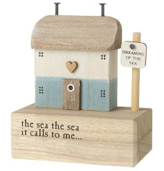A rustic wooden house with a blue and white washed finish. Set upon a wooden block with sea poem. 