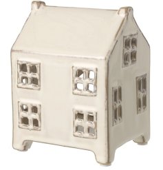 A whimsical house made from ceramic with cut out windows, stood on 4 mini legs.