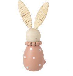 A wooden simplistic bunny wearing a bead necklace and polkadot dress.