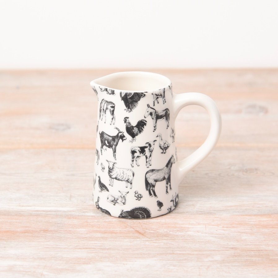 A white jug dressed with black fine detail illustrations of farm animals. 