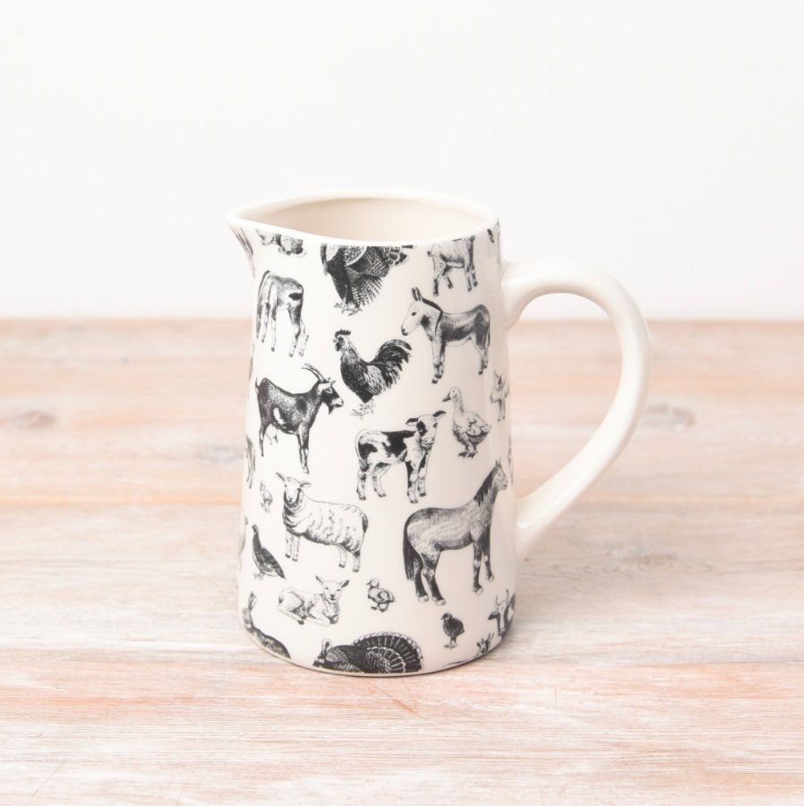 Adorned with farmyard animals, a white and black jug with a chunky white handle.
