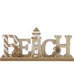 This wooden 'Beach' plaque adorned with shells and boat additions is perfect for styling in a coastal themed home. 