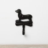 A simplistic wall hook made from cast iron featuring a Dachshund dog stood on top of a bone. 