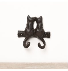 A simplistic cast iron wall hook featuring a pair of cats with their tails as the hooks. 