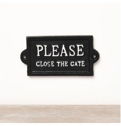 A jet black cast iron sign with white ' please close the gate' text.