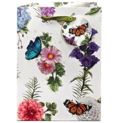 A pretty gift bag featuring a floral display with floating butterflies, complete with sage green ribbon handles and a