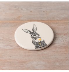 A sweet coaster made from ceramic featuring a cute rabbit holding a single daisy design. 