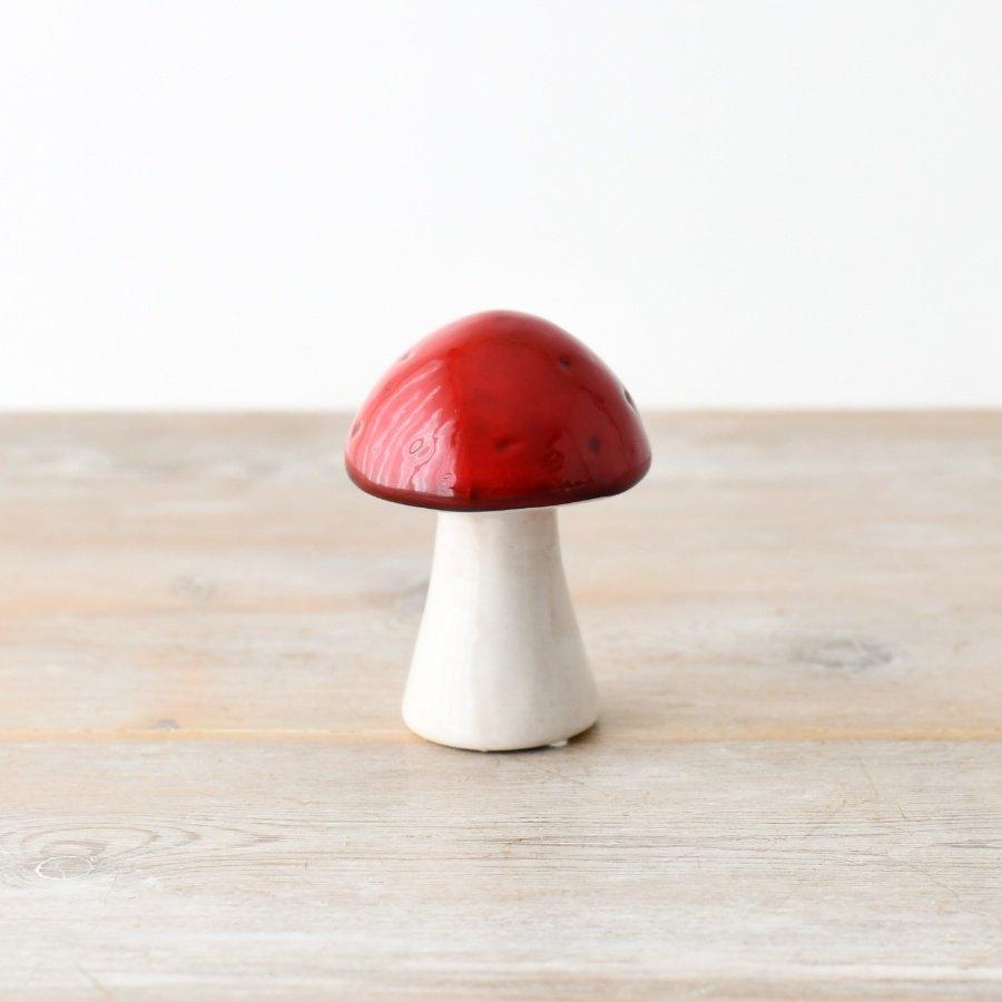 A ceramic mushroom with a natural stem and red glazed top.