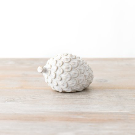 A white ceramic artichoke decor piece that is perfect for displaying on a mantel or fireplace.