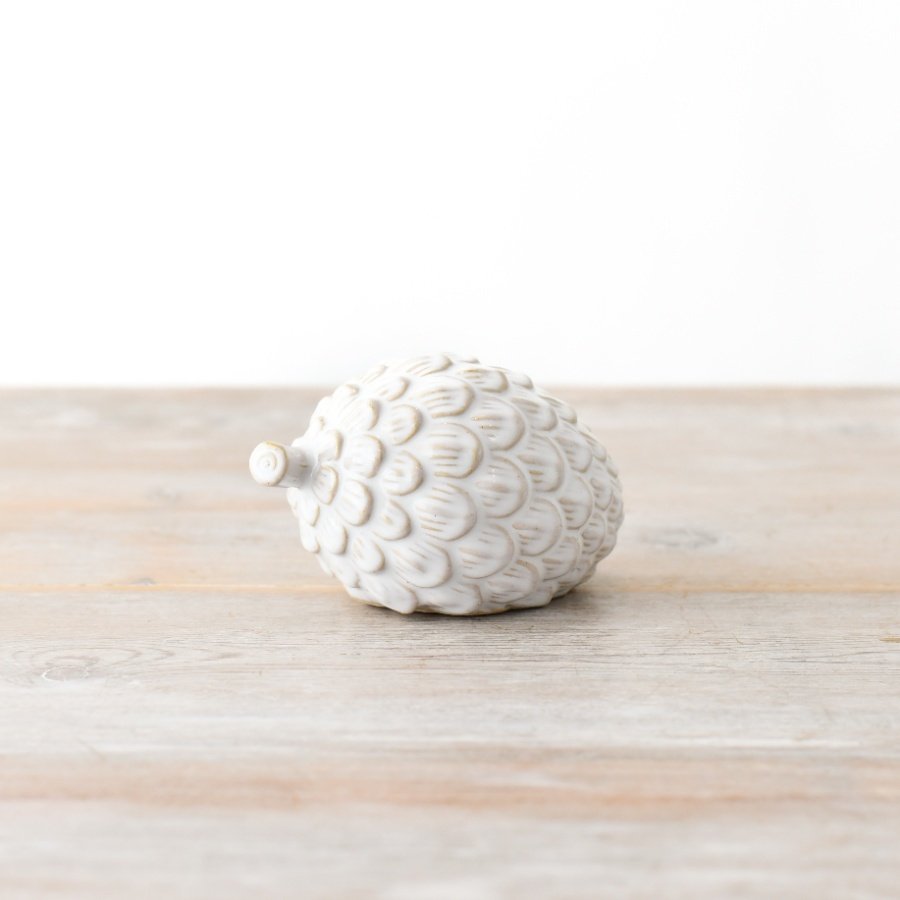 A pinecone decorative item in a glossy white finish.