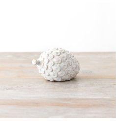 A white ceramic Pinecone decor piece that is perfect for displaying on a mantel or fireplace.
