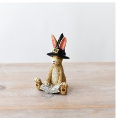 A cute bunny rabbit adorned with a book of spells and a bewitching witches hat.